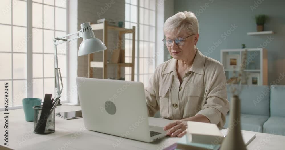 Senior caucasian lady having video chat with relatives or consulting with doctor during self-isolation, using laptop computer at home 4k footage Senior caucasian lady having video chat with relatives or consulting with doctor during self-isolation, using laptop computer at home 4k footage