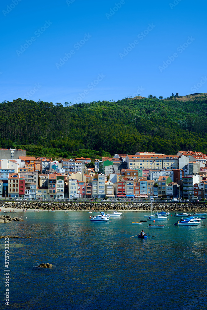 Sea port of a Guarda. Colorful buildings on the beachfront with green mountains in the background. Seascape with boats buildings and green mountain