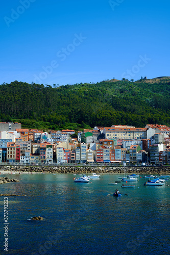 Sea port of a Guarda. Colorful buildings on the beachfront with green mountains in the background. Seascape with boats buildings and green mountain