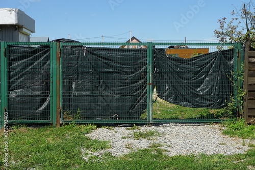 green metal gates made of iron mesh and black cellophane on the street