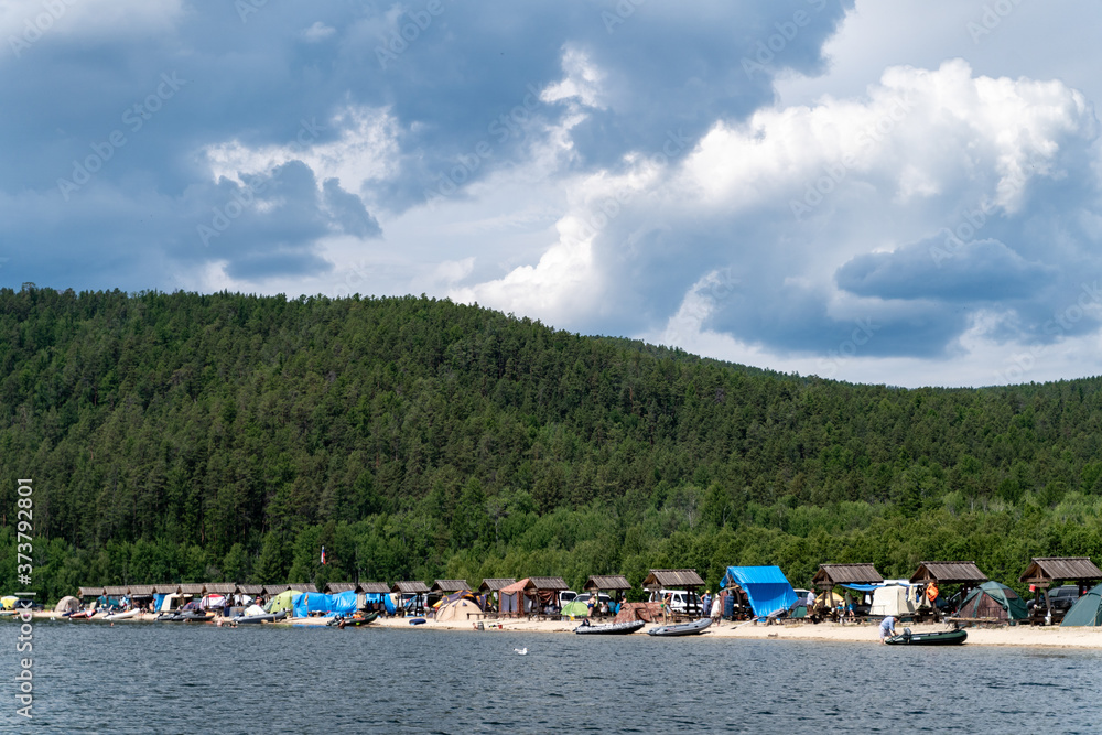 Russia, Irkutsk region, Baikal lake, July 2020: camping tents and tourists on baikal shore, from water view Russia, Irkutsk region, Baikal lake, July 2020: camping tents and tourists on baikal shore, from water view