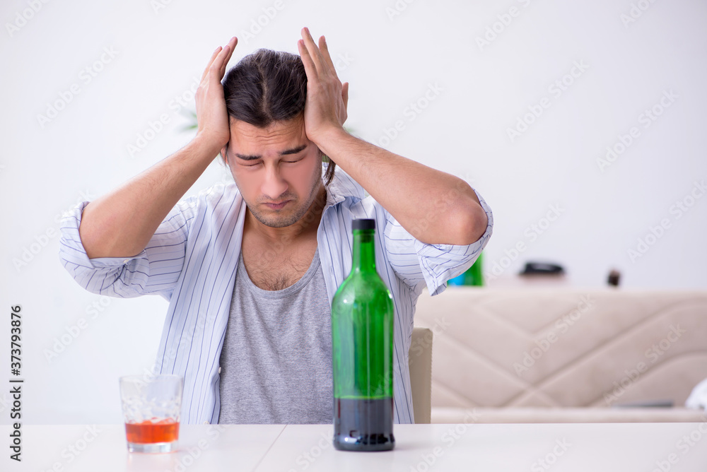 Young male alcoholic drinking whiskey at home Young male alcoholic drinking whiskey at home
