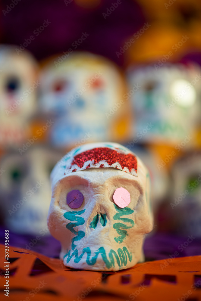 Calaveras de azúcar en fondo de cempasúchil y papel picado ofrenda día de muertos decoración tradición ancestral mexicana  close up fondo desenfocado