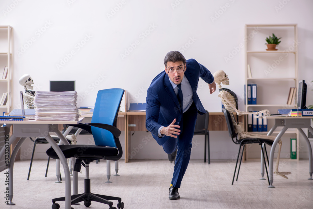 Young male employee with skeletons in the office Young male employee with skeletons in the office