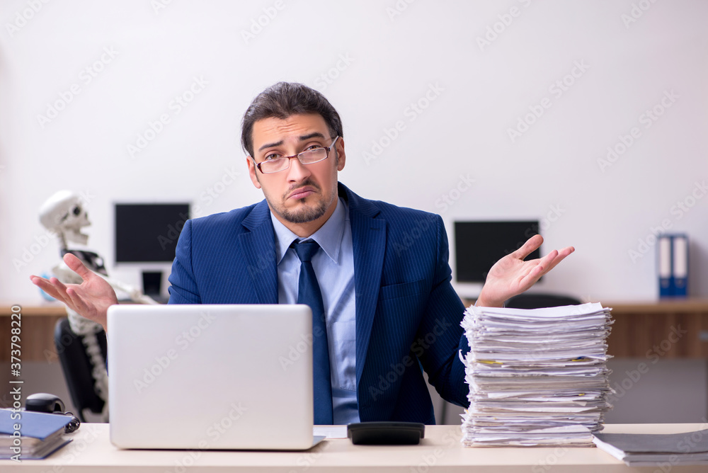Young male employee with skeletons in the office Young male employee with skeletons in the office