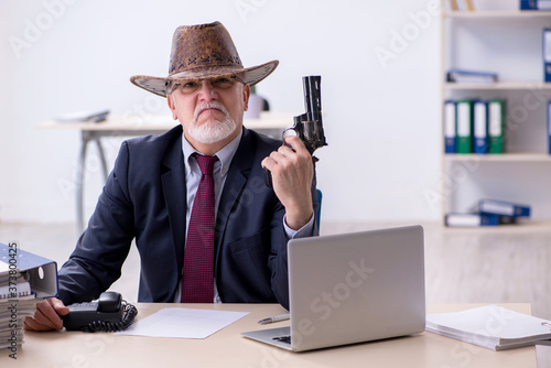 Fotografie Funny old boss in cowboy hat in the office