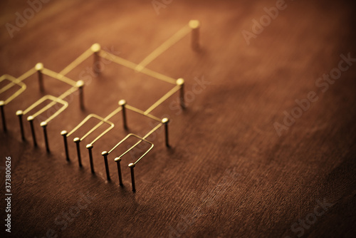 Hierarchy  command chain  company   organization structure or layer and grouping concept image. Top down structure made from gold wires and nails on rustic wooden surface. Shallow depth of field.