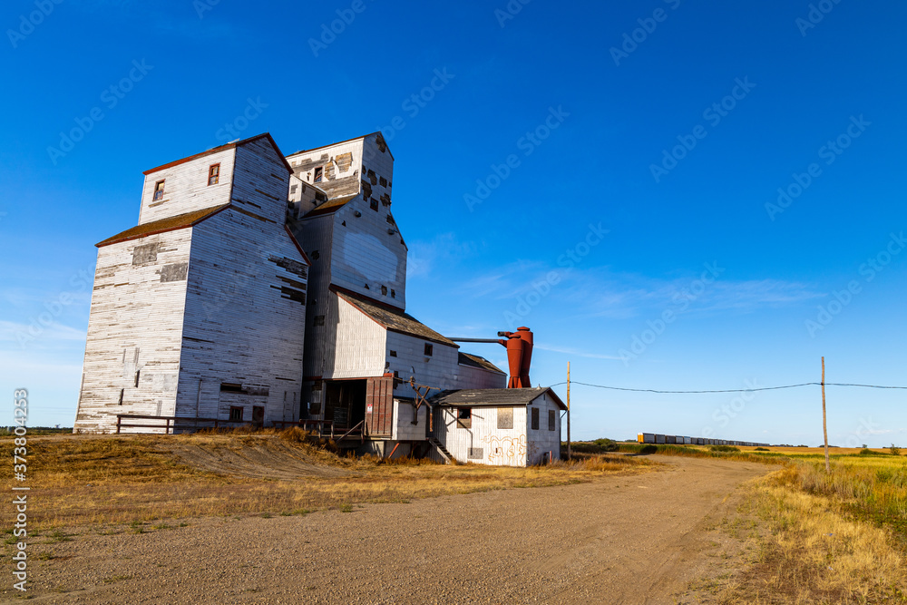Fototapeta premium An old abandoned grain elevator in the town of Leney in the prairie province of Saskatchewan, Canada. These elevators were once used to store wheat and other grains before it was loaded onto trains