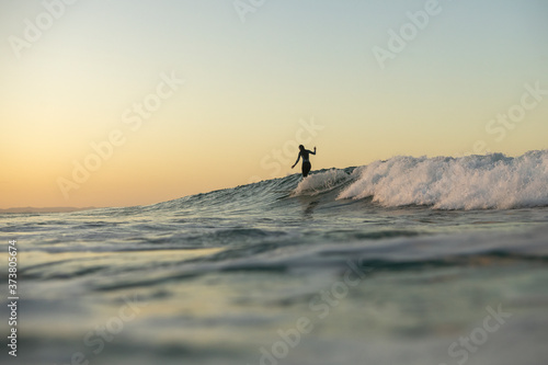 Surfer girl at sunset, Byron Bay Australia