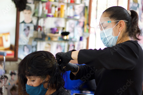 Hairdresser wearing a mask doing her client's hair