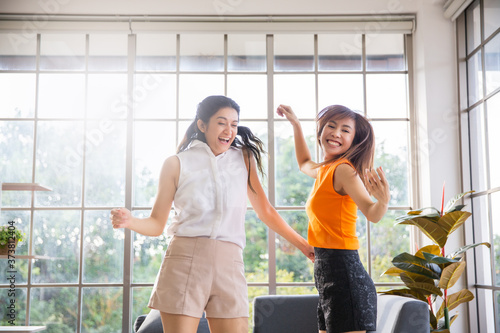 Fototapeta Naklejka Na Ścianę i Meble -  Two asian girl friend dancing in living room at home, Happy woman stay home