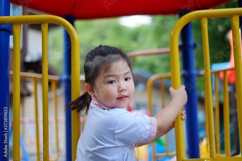 Fotografi A cute young Asian girl in school uniform is climbing up a jungle gym at the school playground during recess hour