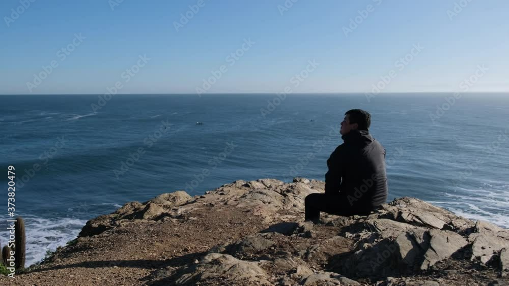 man taking off his face mask pandemic trip new way of traveling man looks from a viewpoint in punta de lobos surf point in chile with face mask in the new normal of chile healthy covid free cactus