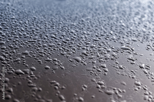 The surface of the car's body is covered with drops of water during the rain.
