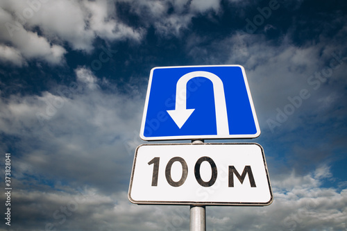 U-turn place road sign on blue sky with clouds. Wrong turn