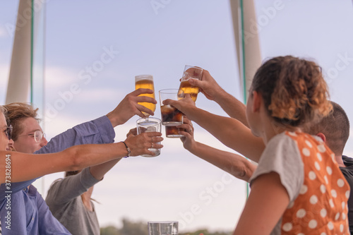 A group of young people raising their drinks for a toast on an out of focus background. Friendship and lifestyle concept.