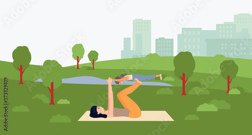 Mother and daughter stretching on yoga mat on summer park