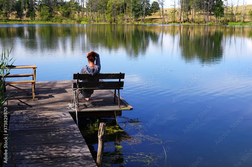 woman sitting on a wooden pier on the lake woman sitting on a wooden pier on the lake