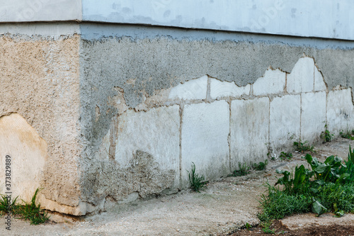 Plaster peeling off brick wall. The foundation of a residential building is gradually collapsing