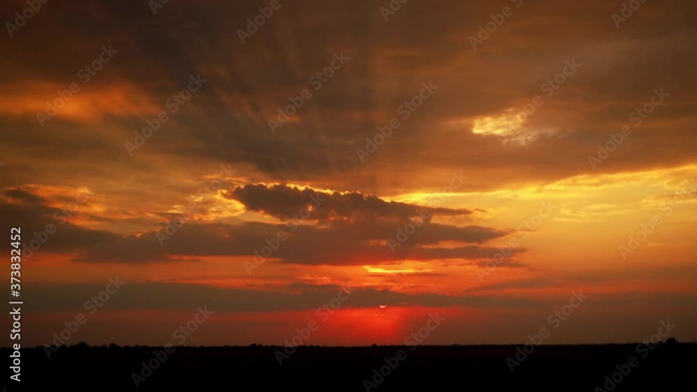Slow motion of the sunset. The rays make their way through the floating clouds. The sky is in orange colors. A dramatic scene in the sky. Slow motion of the sunset. The rays make their way through the floating clouds. The sky is in orange colors. A dramatic scene in the sky.