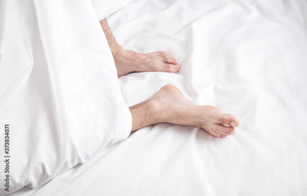Male feets on bed in morning. Male feets on bed in morning.