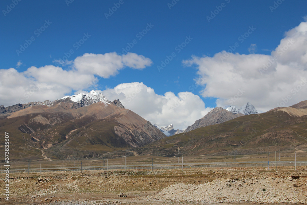 View of ice mountains and Qinghai–Tibet Railway track with the dramatic sky in Tibet, China View of ice mountains and Qinghai–Tibet Railway track with the dramatic sky in Tibet, China