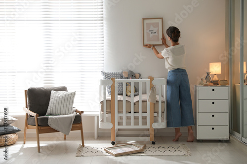 Decorator hanging picture on wall in baby room. Interior design © New Africa