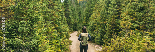 Autumn hiker woman hiking in forest nature panoramic background. Travel outdoors girl going camping in Canada banner.