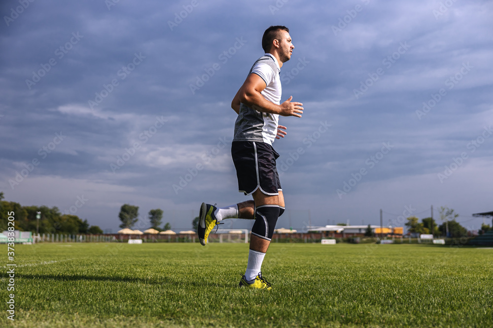 Full length of soccer player in shape running on the field.