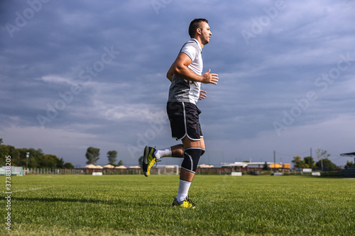 Full length of soccer player in shape running on the field.