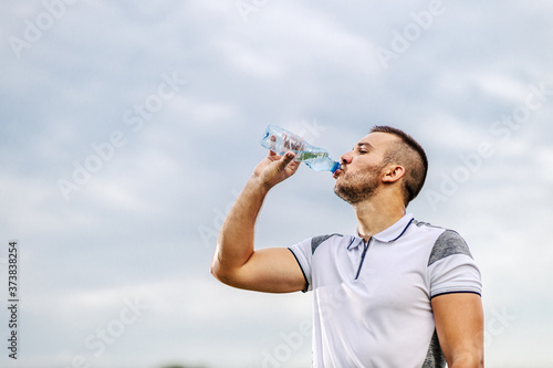 Fototapeta Naklejka Na Ścianę i Meble -  Tired thirsty soccer player on shape taking a break and drinking water.