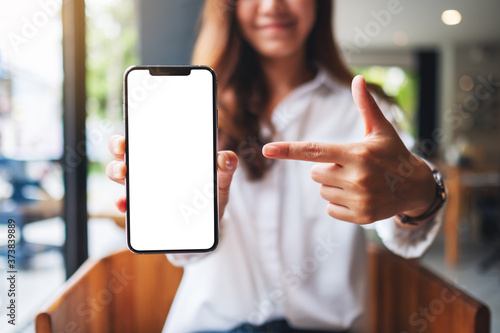 Mockup image of a beautiful woman pointing finger at a mobile phone with blank white screen photo