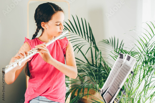 Photo Girl playing the flute at home.