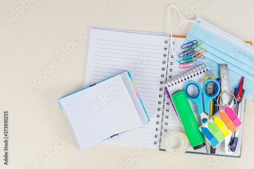 Shopping cart with school supplies, protective mask, alcohol gel. Back to school during a covid-19 pandemic.