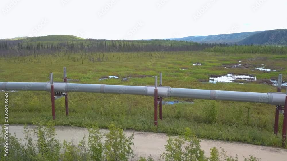 Crude oil pipeline running through vast landscape near Prudhoe Bay, Alaska, USA. Side on medium drone shot Crude oil pipeline running through vast landscape near Prudhoe Bay, Alaska, USA. Side on medium drone shot