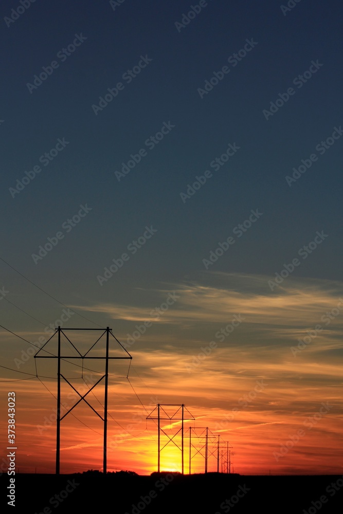 Kansas colorful Sunset with clouds and sky with power lines and poles silhouettes