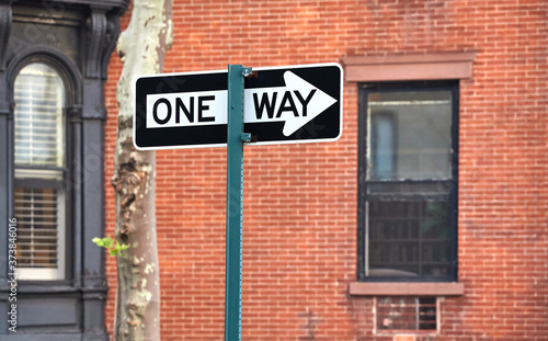 One way street sign with old building in background, selective focus, New York, USA.