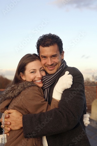Man and woman in winter clothing hugging at the rooftop