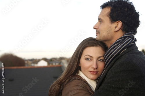 Man and woman in winter clothing hugging  at the rooftop