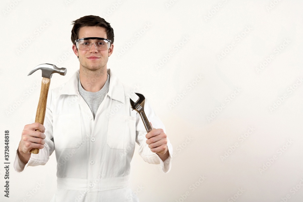 Man with safety goggles holding a hammer and adjustable spanner in each hand Man with safety goggles holding a hammer and adjustable spanner in each hand