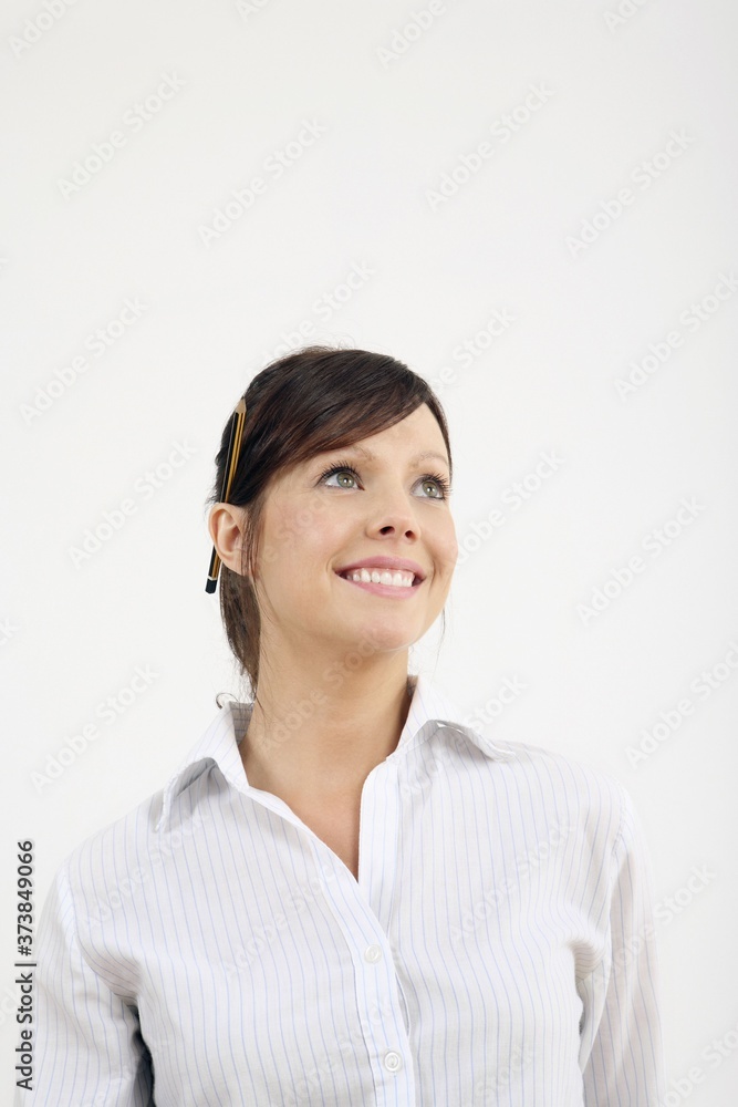 Woman with pencil on ear smiling while looking up Woman with pencil on ear smiling while looking up
