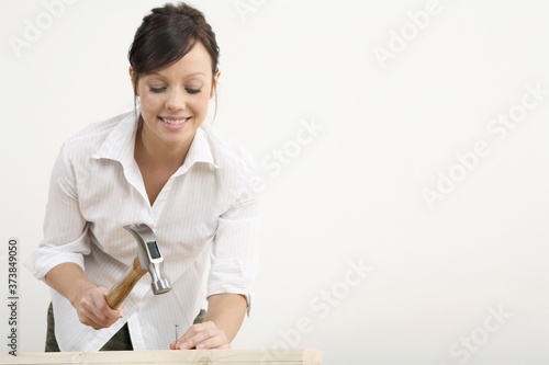 Obraz na plátně Woman hammering nail into wood
