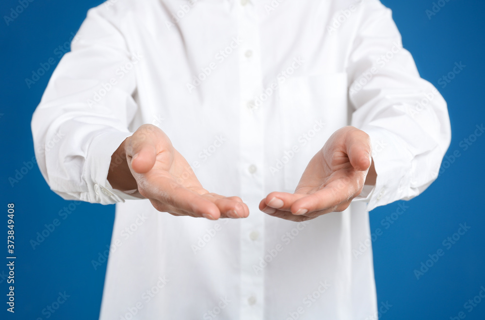 Woman holding something against blue background, focus on hands Woman holding something against blue background, focus on hands