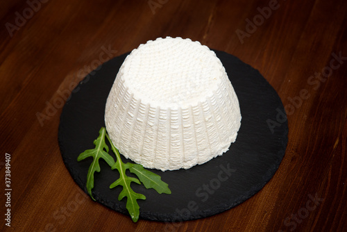 Head of soft white cheese, feta cheese on black plank, top view, close-up