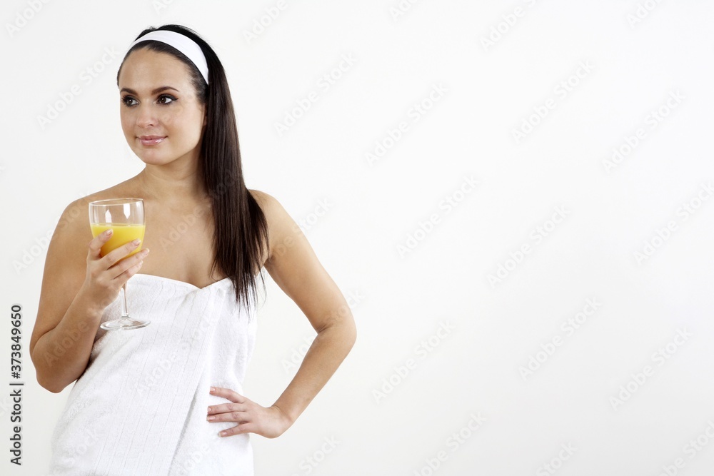 Woman wrapped in towel holding a glass of orange juice