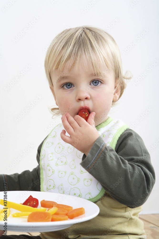 Preschooler with baby bib eating vegetables Preschooler with baby bib eating vegetables