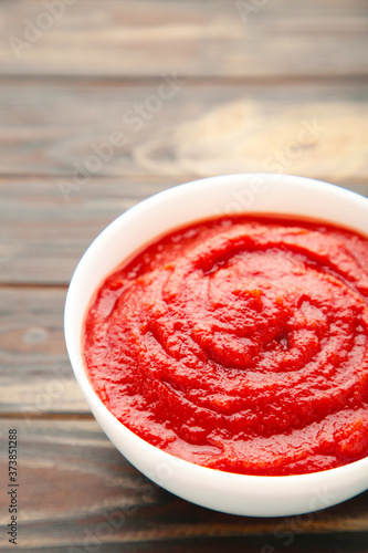 Bowl of ketchup or tomato sauce on brown wooden table