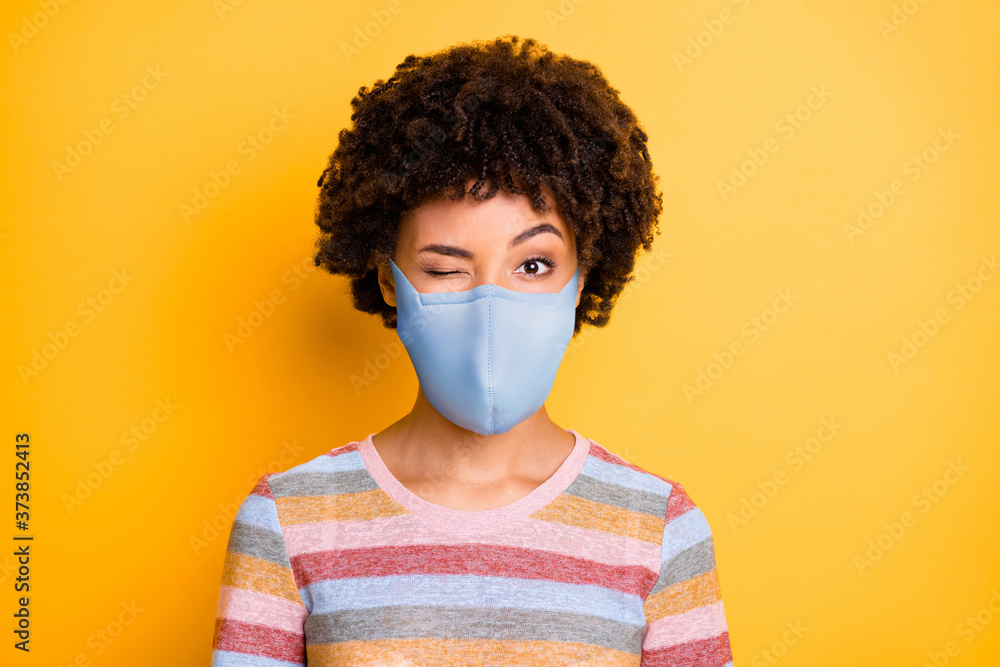 Close-up portrait of her she healthy attractive funky wavy-haired girl wearing safety reusable mask winking stop viral respiratory disease isolated bright vivid shine vibrant yellow color background Close-up portrait of her she healthy attractive funky wavy-haired girl wearing safety reusable mask winking stop viral respiratory disease isolated bright vivid shine vibrant yellow color background