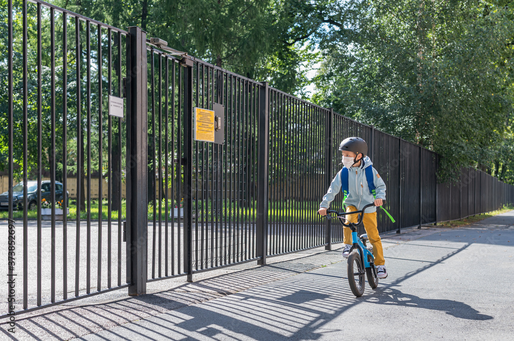 A masked boy rides a Bicycle to school. Back to school. New normal. A masked boy rides a Bicycle to school. Back to school. New normal.