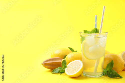 Natural freshly made lemonade with squeezer on yellow background, space for text. Summer refreshing drink